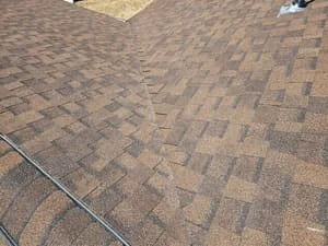 Newly installed asphalt shingle roof with dimensional shingles in brown and gray tones, staggered pattern