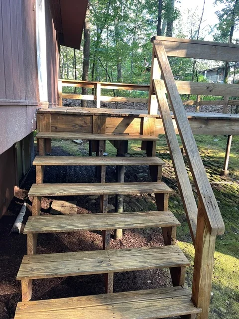 Wooden deck stairs with handrail, pressure-treated lumber treads and support beam
