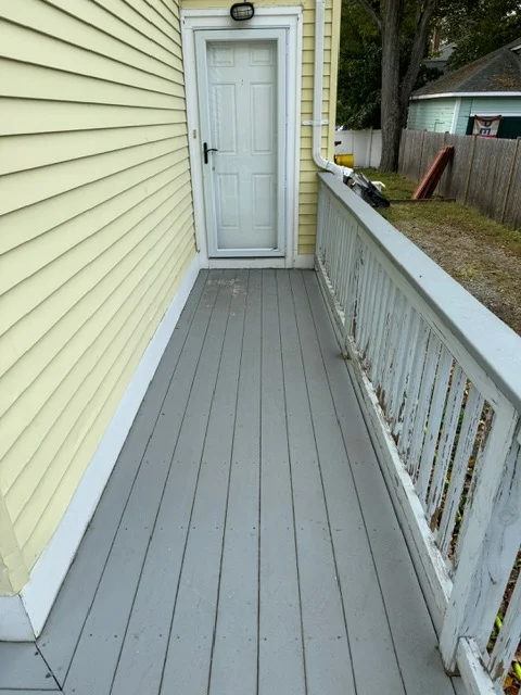 Gray composite deck with white vinyl railing and freshly painted yellow siding
