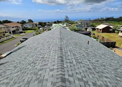 Gray architectural shingles installed on residential roof with ridge caps and proper alignment