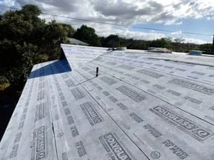 Asphalt shingle roof installation with white underlayment and blue starter strip