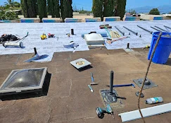 Flat roof with multiple skylights, membrane installation, and roofing materials staged on roof deck