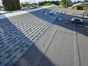 Asphalt shingle roof installation with blue-gray dimensional shingles in staggered pattern