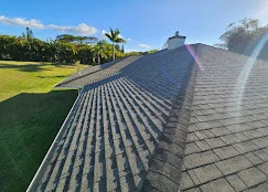 Newly installed asphalt shingle roof with dimensional shingles and ridge caps on residential home