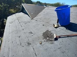 Flat roof with patched membrane sections and repair work in progress