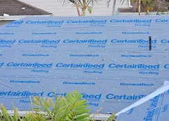 Blue synthetic roof underlayment installed over roof deck with proper overlap and securing