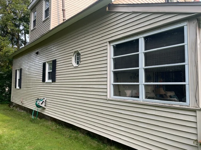 Horizontal vinyl siding installation with soffit, fascia, and large multi-pane garage door on residential home