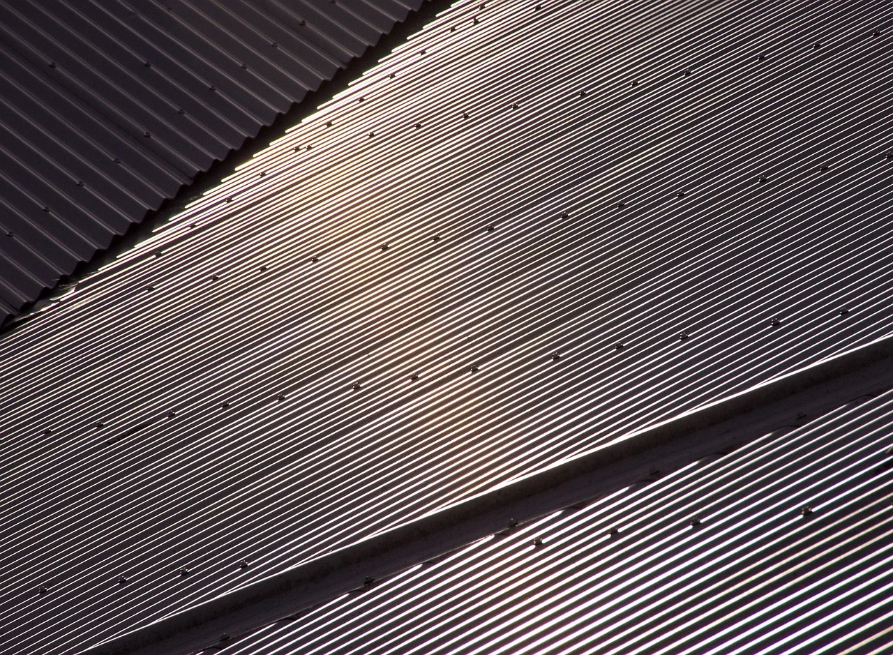 Corrugated metal roof panels with ribbed profile and fasteners, light and dark finishes