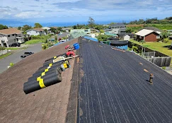 Aerial view of residential roof with new asphalt shingles and black underlayment during installation