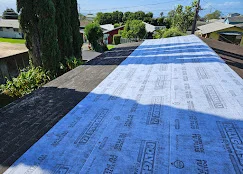 Blue roof underlayment installed on residential roof deck with proper overlap and securing