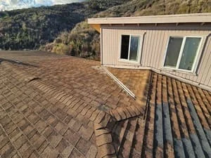Newly installed asphalt shingle roof with brown dimensional shingles and metal flashing details