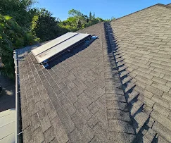 Newly installed asphalt shingle roof with chimney flashing and valley work