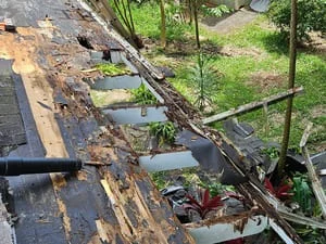 Damaged roof with deteriorated shingles, exposed wood decking, and fallen debris