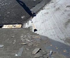 Roof tear-off showing exposed wood sheathing and removed asphalt shingles
