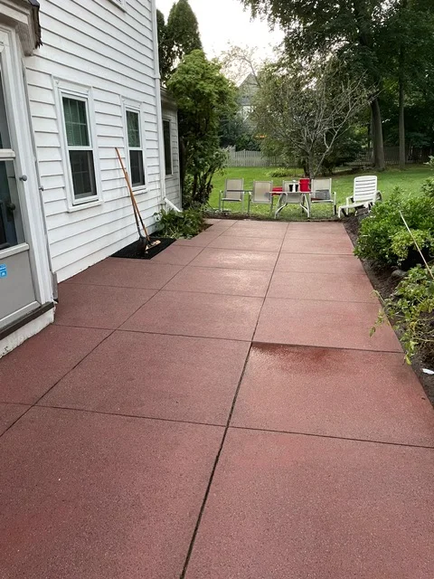 Stamped concrete patio with control joints adjacent to white house siding