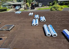 Bundles of asphalt shingles staged on driveway for roof replacement installation